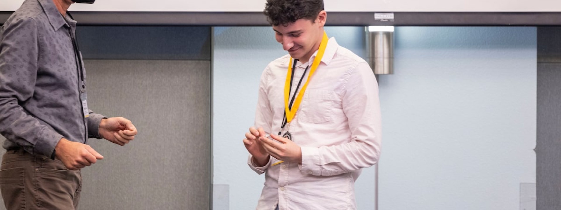 Male student in pink button up on stage looking at medallion