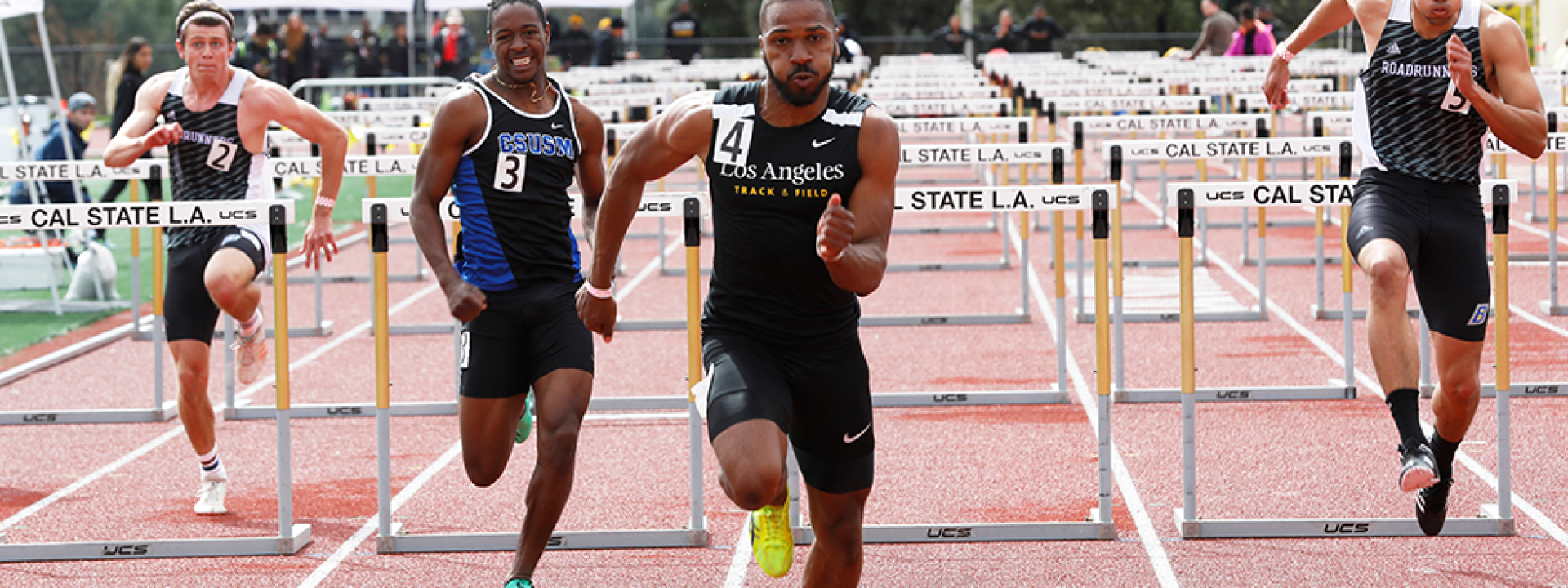Image of a Cal State LA track star leading a hurdle race. 
