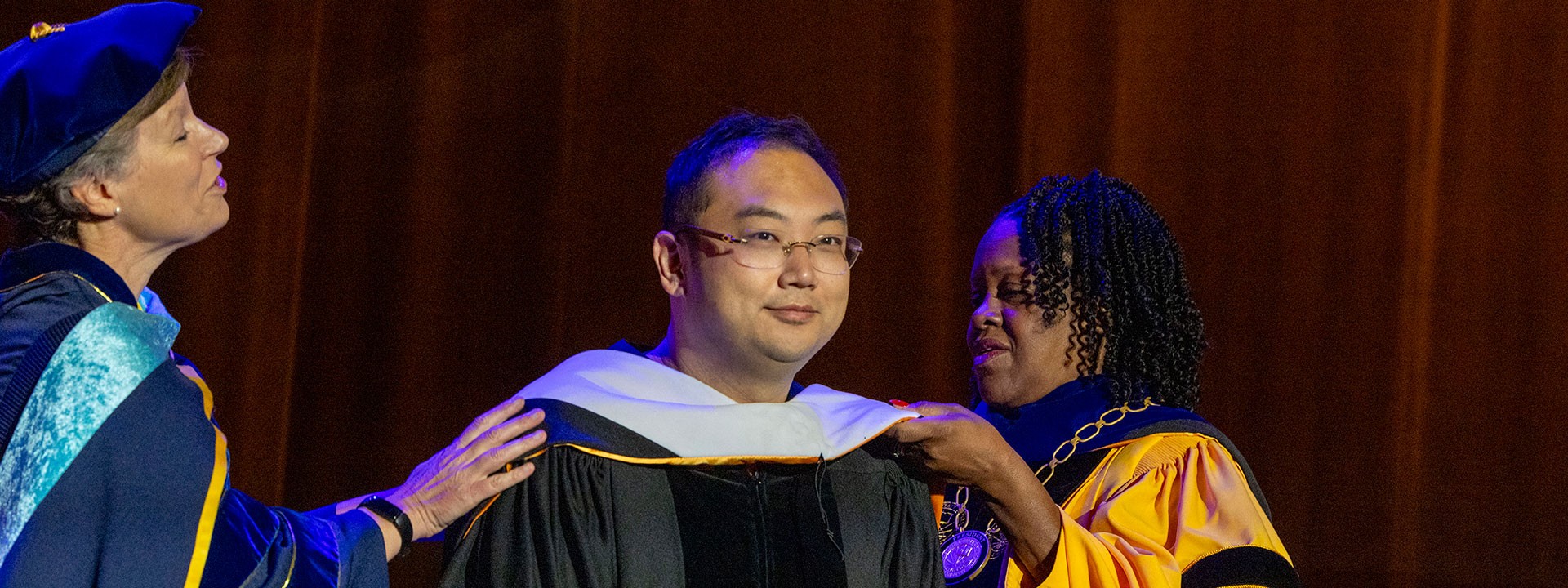 Kevin Xu being hooded by Provost Lattimer and President Eanes