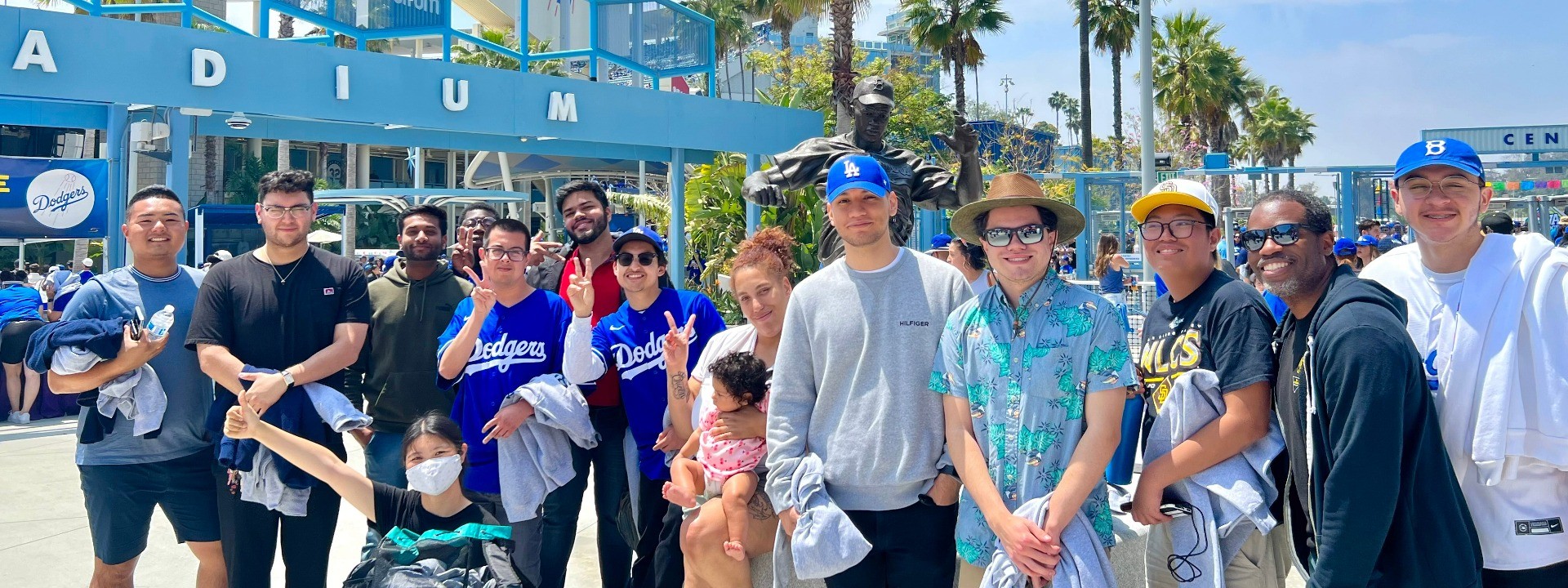 Group of men and women standing and smiling in front of a blue structure