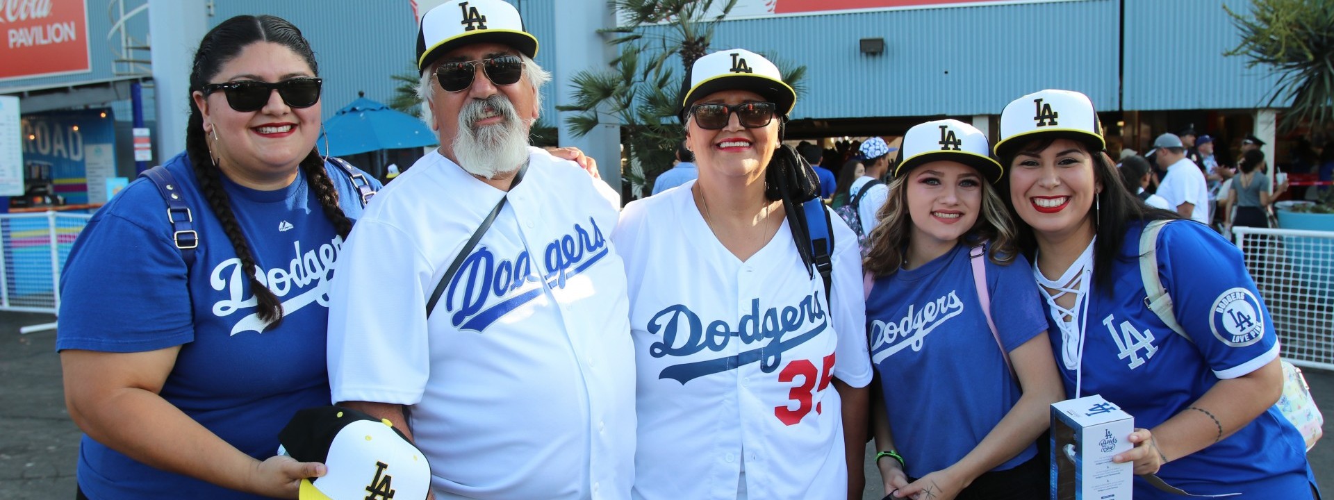 Five people posing with Cal State LA baseball caps at Dodger Stadium