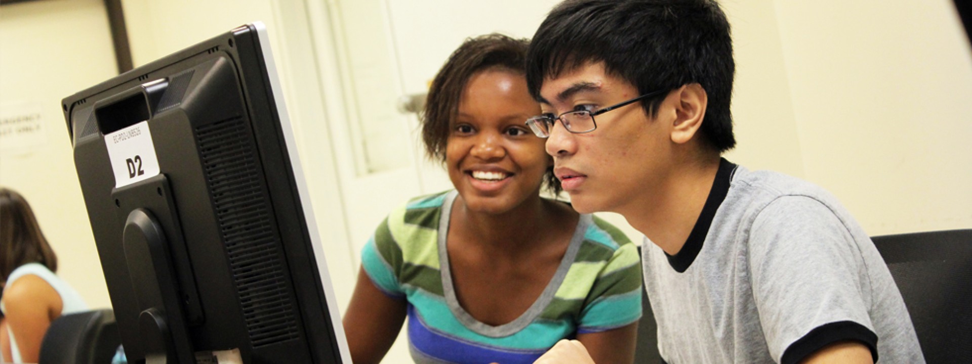 Two Honors College students facing a computer screen intently. 