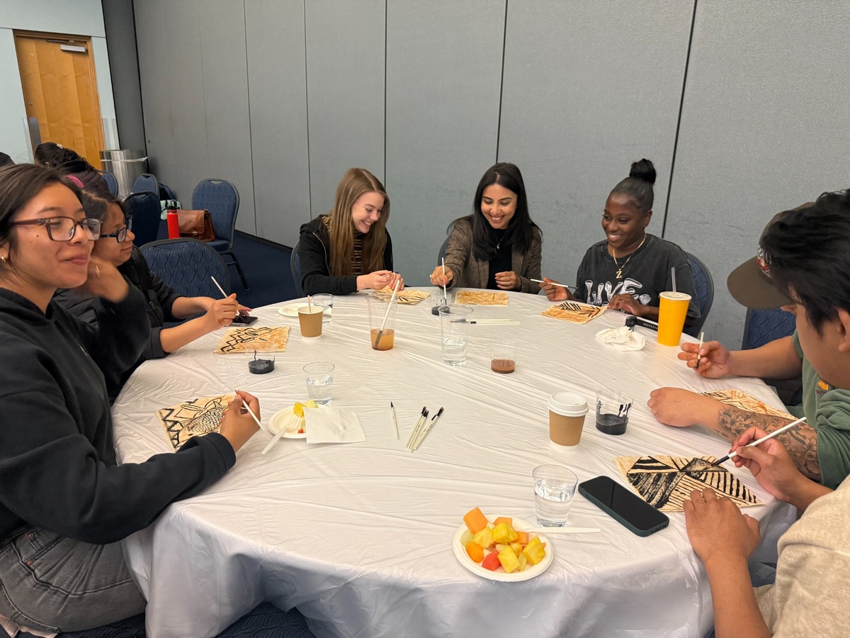 Students sit around a table creating traditional Tongan tapa art during a cultural workshop at Cal State LA.