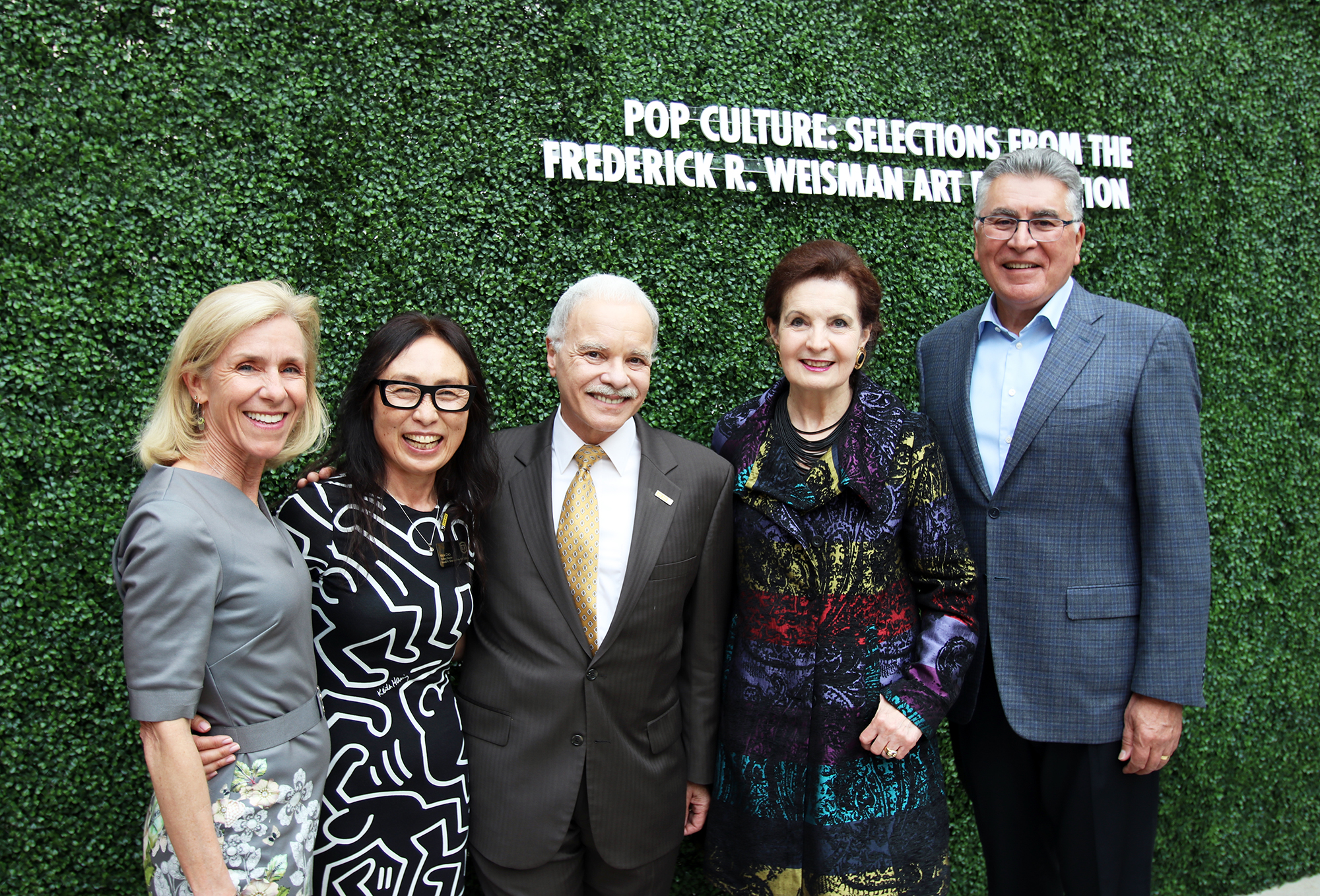 Five people stand in front of green hedge that reads, Pop Culture: Selections from the Frederick R. Weisman Art Foundation