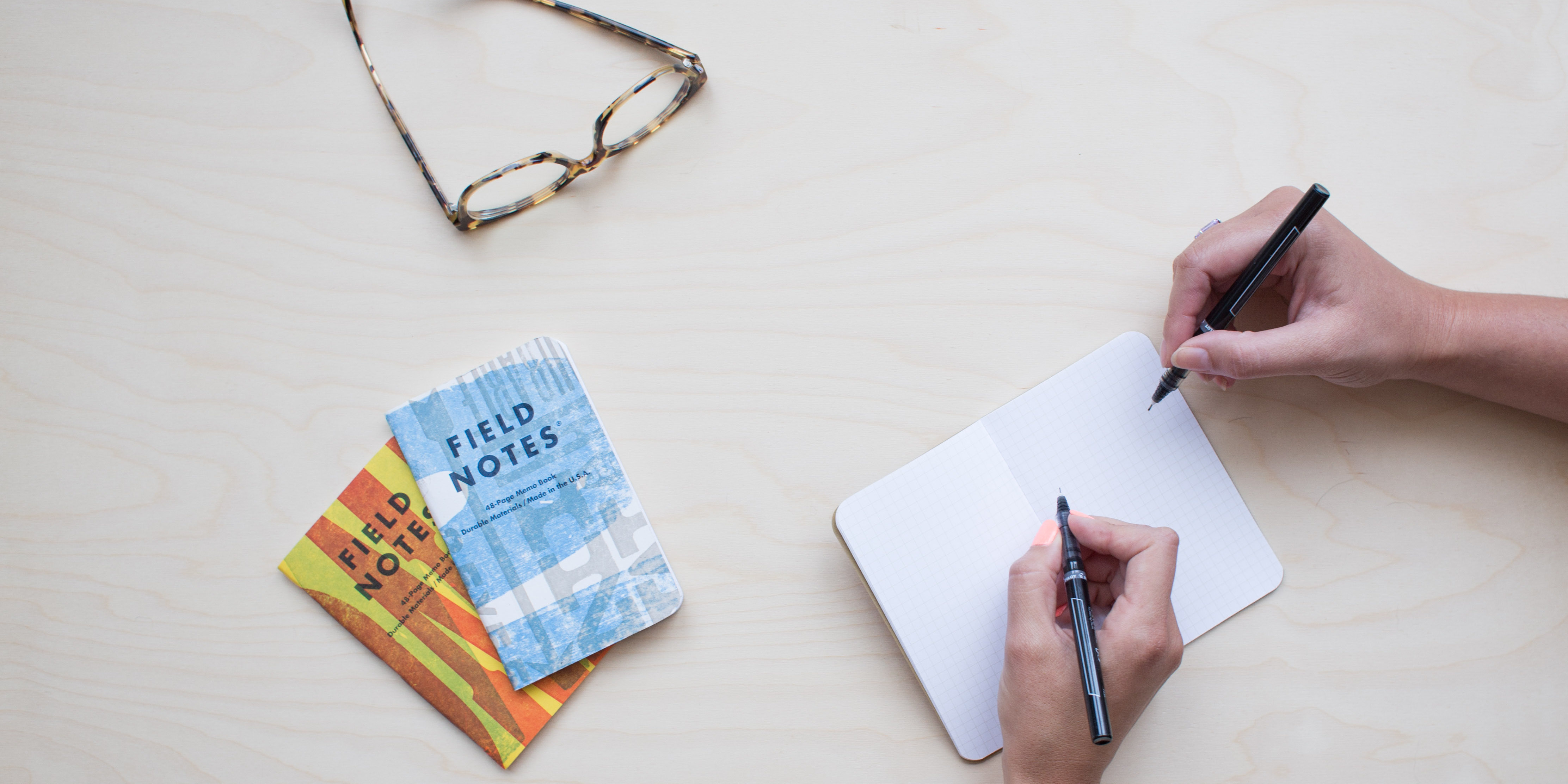 Two people's hands write in the same notebook